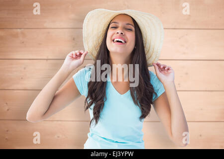 Composite image of happy young brunette wearing sunhat Stock Photo