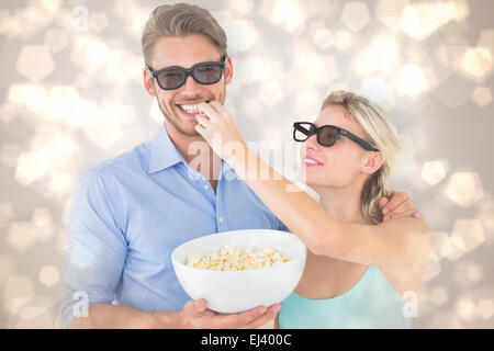 Composite image of happy young couple wearing 3d glasses eating popcorn Stock Photo