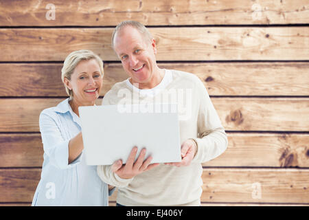 Composite image of happy mature couple using laptop Stock Photo