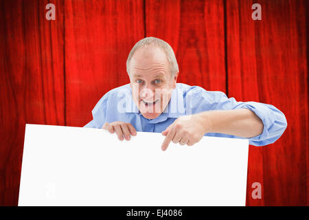 Composite image of mature man smiling at camera and pointing Stock Photo