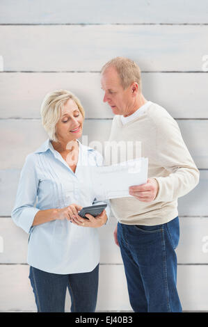Composite image of mature couple working out their bills Stock Photo