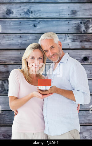 Composite image of happy couple holding miniature model house Stock Photo