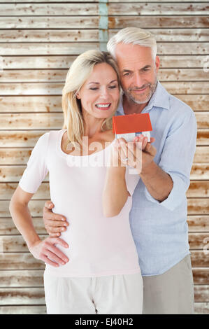 Composite image of happy couple holding miniature model house Stock Photo