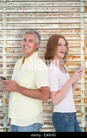 Composite image of casual couple sending text messages Stock Photo