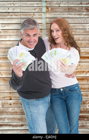 Composite image of casual couple showing their cash Stock Photo