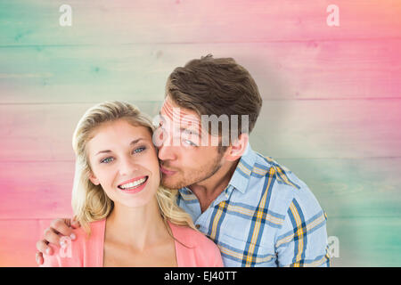 Composite image of handsome man kissing girlfriend on cheek Stock Photo