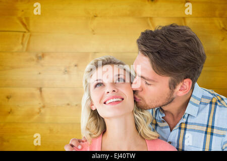 Composite image of handsome man kissing girlfriend on cheek Stock Photo