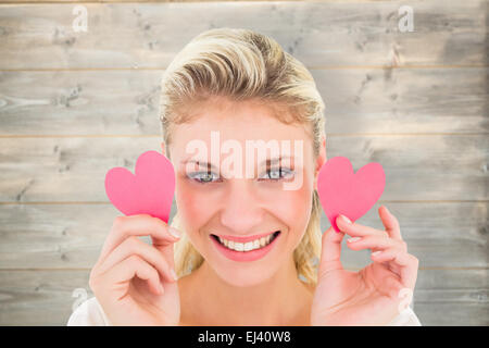 Composite image of attractive young blonde holding little hearts Stock Photo