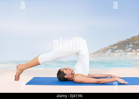 Composite image of fit woman doing the plough posture in fitness studio Stock Photo