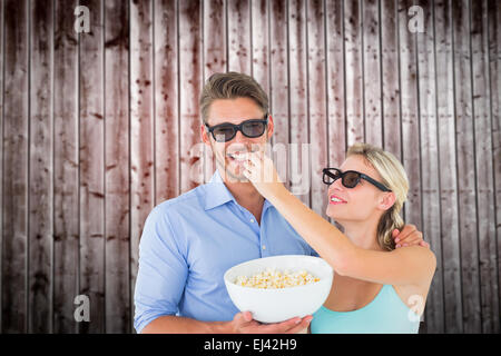 Composite image of happy young couple wearing 3d glasses eating popcorn Stock Photo