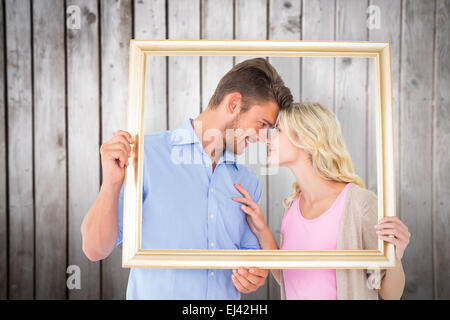 Composite image of attractive young couple holding picture frame Stock Photo