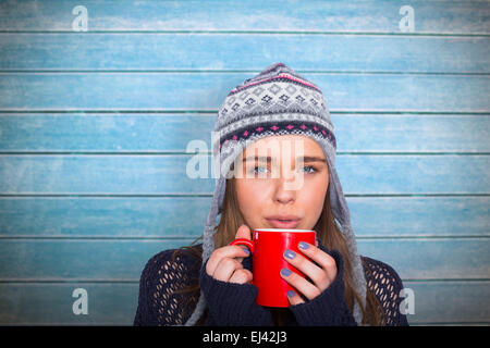 Composite image of beautiful woman in warm clothing drinking coffee Stock Photo