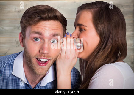 Composite image of woman whispering secret into friends ear Stock Photo