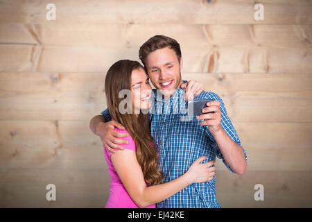 Composite image of cheerful young couple taking selfie with smart phone Stock Photo