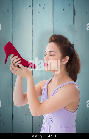 Composite image of elegant brunette kissing a shoe Stock Photo