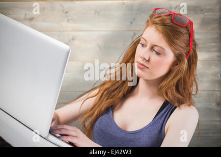 Composite image of pretty redhead working on laptop Stock Photo