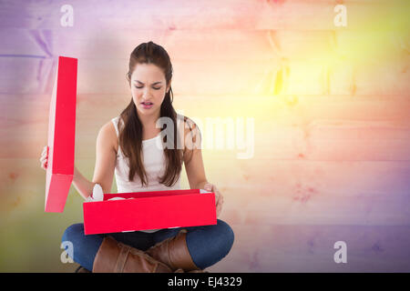 Composite image of unhappy brunette opening present Stock Photo