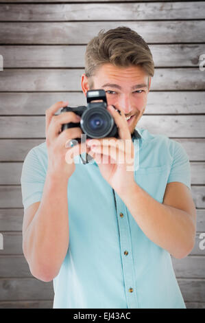 Composite image of handsome young man holding digital camera Stock Photo