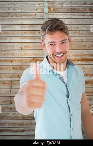 Composite image of handsome young man showing thumbs up to camera Stock Photo
