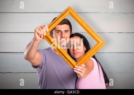 Composite image of young couple holding up frame Stock Photo