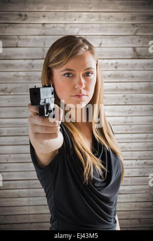 Composite image of femme fatale pointing gun at camera Stock Photo