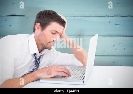 Composite image of focused businessman working on his laptop Stock Photo