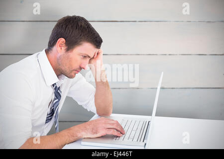 Composite image of focused businessman working on his laptop Stock Photo