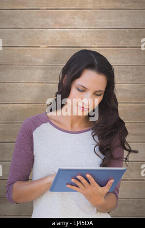 Composite image of brunette using tablet pc Stock Photo