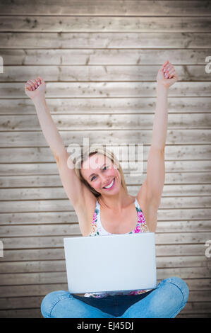 Composite image of pretty blonde cheering and having laptop Stock Photo