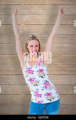 Composite image of happy blonde cheering with arms up Stock Photo