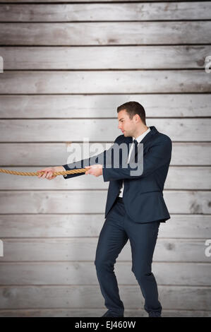 Composite image of young businessman pulling a rope Stock Photo
