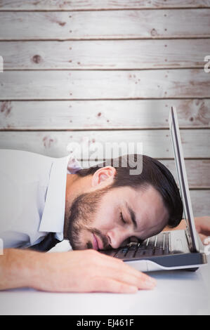 Composite image of businessman resting head on laptop keyboard Stock Photo