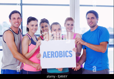 Aerobics against portrait of a group of fitness class holding blank paper Stock Photo