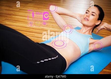 Composite image of fit brunette doing sit ups in fitness studio Stock Photo