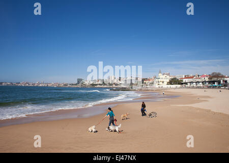 Women walk their dogs on a beach in Estoril, Portugal. Stock Photo