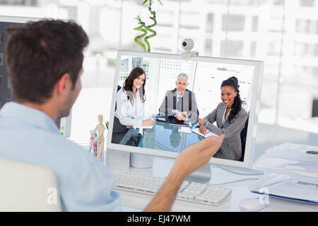 Composite image of smiling director sitting at the desk in front of the window between two employees Stock Photo