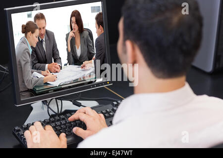Composite image of four serious engineers looking at plans sitting at a table Stock Photo