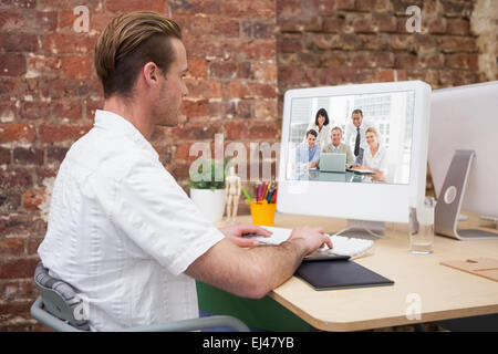 Composite image of happy business people gathered around laptop looking at camera Stock Photo