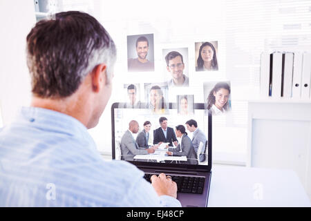 Composite image of man with grey hair using his laptop Stock Photo