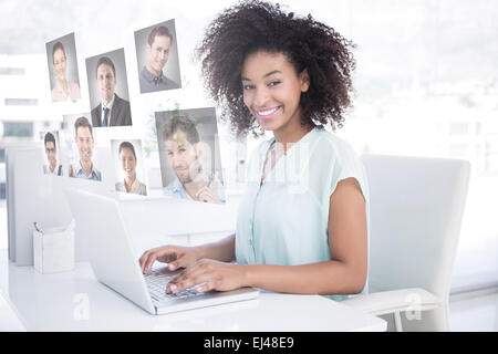 Composite image of happy businesswoman working on her laptop Stock Photo
