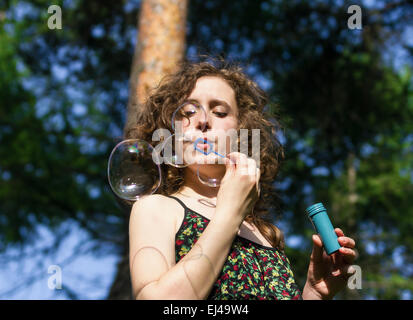 Young pretty woman blowing soap bubbles in park Stock Photo