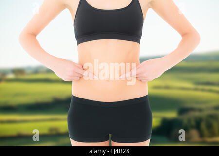 Composite image of closeup mid section of a fit woman with hands on stomach Stock Photo
