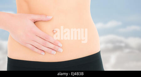 Composite image of closeup mid section of a fit woman with stomach pain Stock Photo