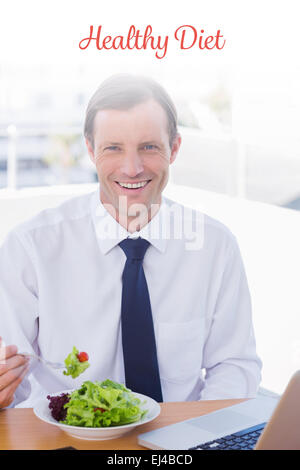 Healthy diet against cheerful businessman eating a salad on his desk Stock Photo