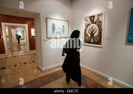 Young woman in traditional Muslim clothes watches contemporary visual art exhibition during 2nd Grand Festival of Art for Peace in Tehran, Iran Stock Photo
