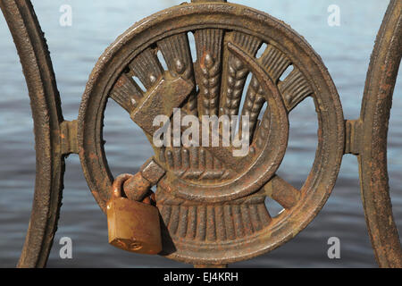Love lock fixed on the hammer and sickle. Soviet time grating on the embankment of the River Daugava in Riga, Latvia. Stock Photo