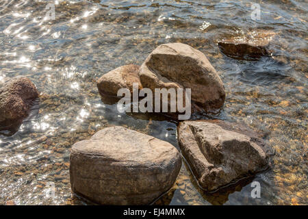 Rocks in crystal clear water and sparkling light, Ullswater, Lake District National Park, England, Great Britain, UK. Stock Photo
