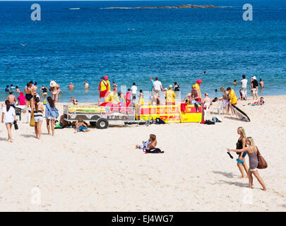 Swimmers, beach visitors, and surf lifesavers on a hot and sunny day by the sea in the Sydney, Australia suburb of Coogee Beach. Stock Photo