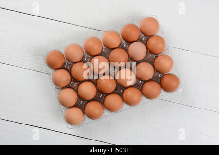 High angle shot of a 24 pack of organic brown eggs on a rustic white wood table. Horizontal format with copy space. Stock Photo