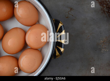 Overhead shot of brown eggs in pot of water. Closeup only half the pot is showing on a well used cooking surface. Stock Photo